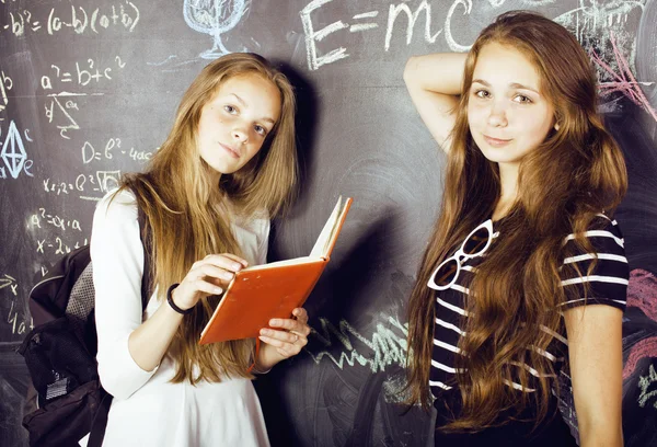 Back to school after summer vacations, two teen girls in classroom with blackboard painted
