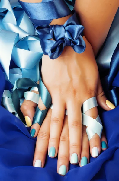 Blue manicure with ribbon close up as a gift