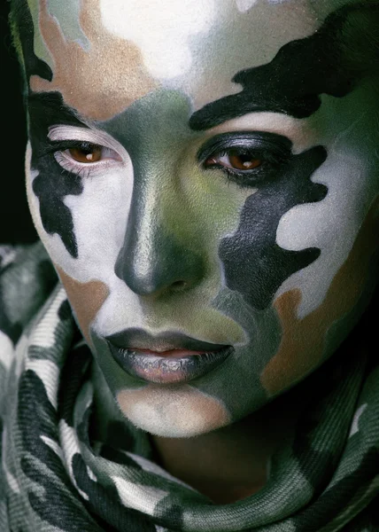 Beautiful young fashion woman with military style clothing and face paint make-up, khaki colored