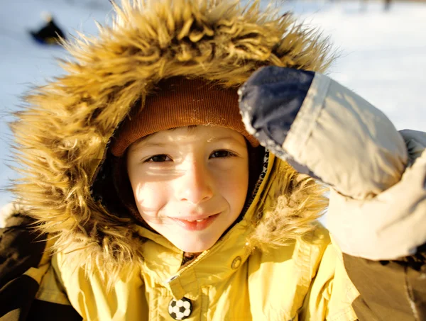 Little cute boy in hood with fur on snow outside