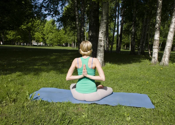 Blonde girl doing yoga in park