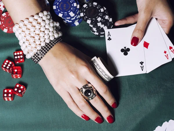 Hands of young caucasian woman with red manicure at casino table close up
