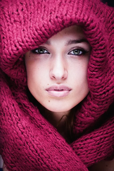 Young pretty woman in sweater and scarf all over her face close