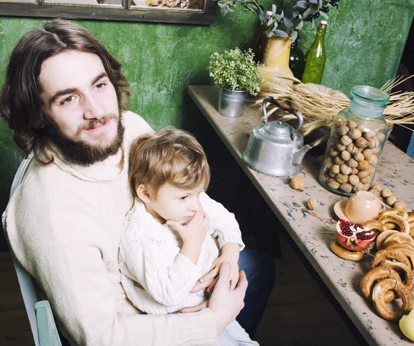 Father with beard holding son at countryside vintage kitchen