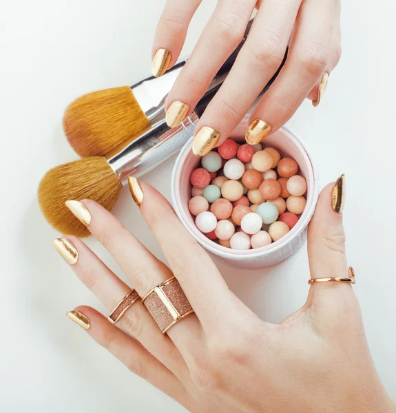 Woman hands with golden manicure  many rings holding brushes, make up artist stuff stylish and pure