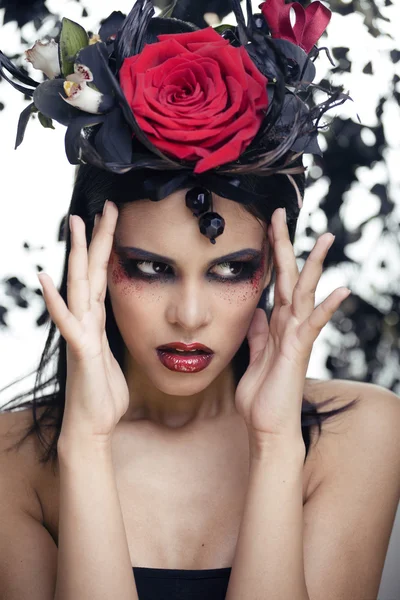 Pretty brunette woman with rose jewelry, black and red, bright make up kike a vampire closeup