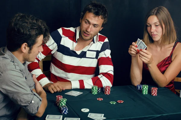 Young people playing poker on black background