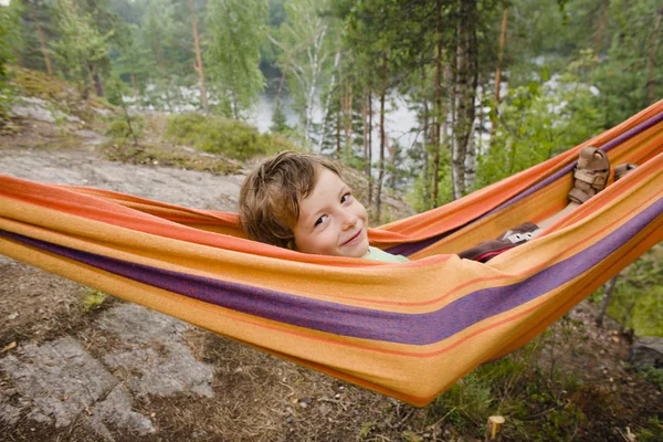 Little cute boy in hammock smiling, forest relax