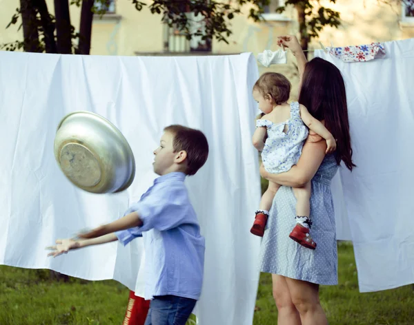 Woman with children in garden hanging laundry outside