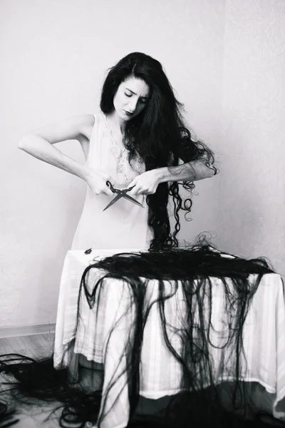 Beauty girl cuting her hair in empty fearing room with cutted hair
