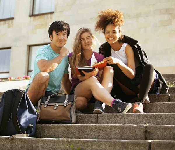 Cute group of teenages at the building of university with books huggings, back to school