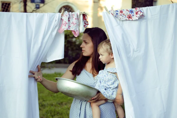 Woman with children in garden hanging laundry outside