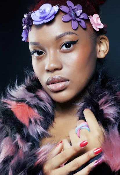 Young pretty african american woman in spotted fur coat and flowers jewelry on head smiling sweet etnic