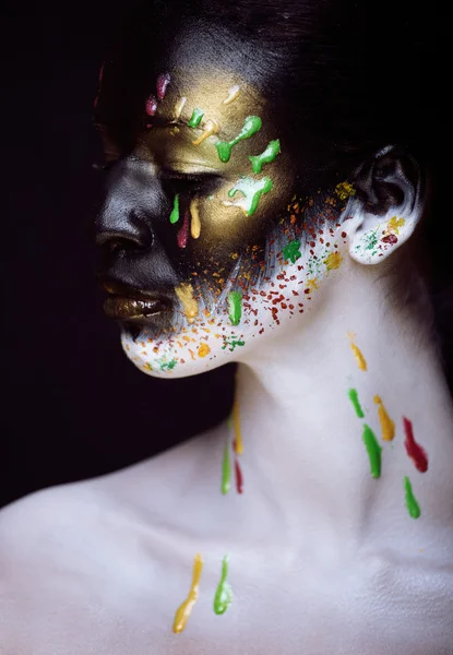 Woman with creative make up closeup like drops of colors, facepaint close up halloween style