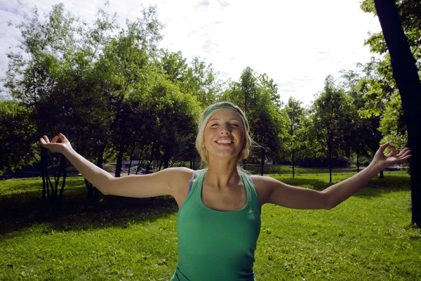 Blonde real girl doing yoga in green park, gymnastic head over hills