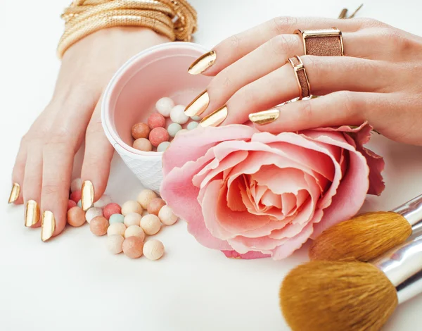 Woman hands with golden manicure and many rings holding brushes, makeup artist stuff stylish, pure close up