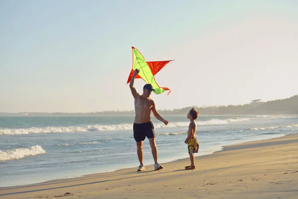 Father with son, sunset at the seacoast with kite, happy family