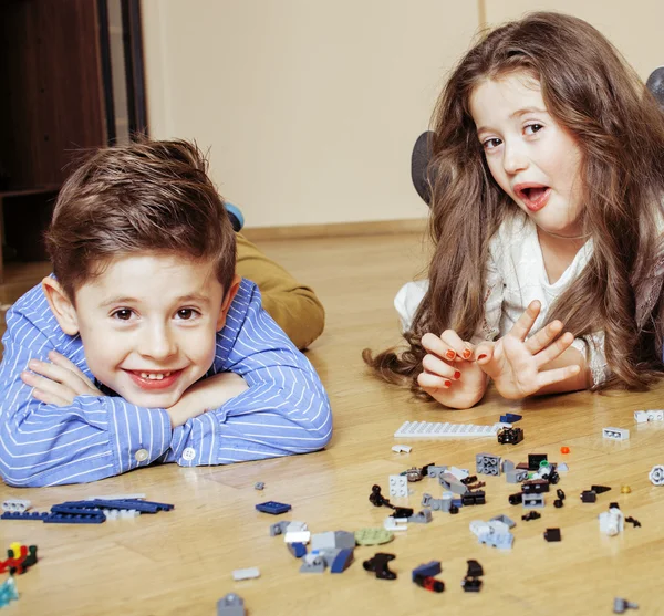 Funny cute children playing lego at home, boys and girl smiling, first education role close up