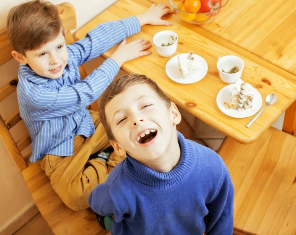 Little cute boys eating dessert on wooden kitchen. home interior. smiling adorable friendship together forever