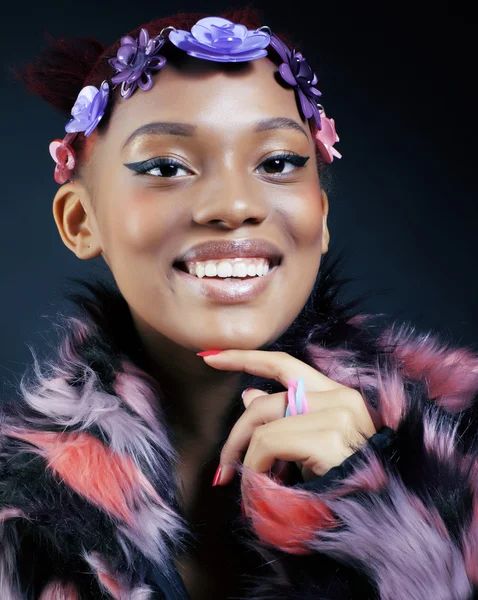 Young pretty african american woman in spotted fur coat and flowers jewelry on head smiling sweet etnic make up bright