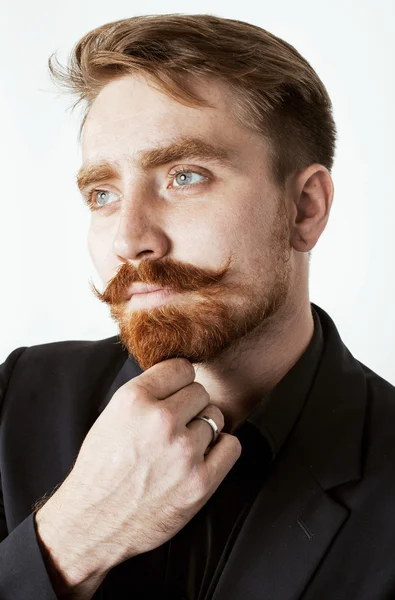 Young red hair man with beard and mustache in black suit on white background