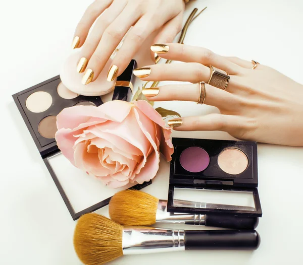 Woman hands with golden manicure and many rings holding brushes, makeup artist stuff stylish, pure close up pink