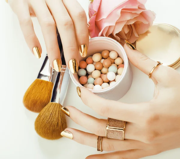 Woman hands with golden manicure and many rings holding brushes, makeup artist stuff stylish, pure close up pink