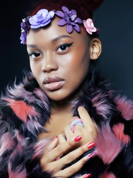 Young pretty african american woman in spotted fur coat and flowers jewelry on head smiling sweet etnic make up bright