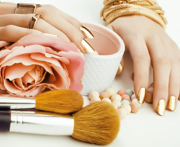 Woman hands with golden manicure and many rings holding brushes, makeup artist stuff stylish, pure close up pink