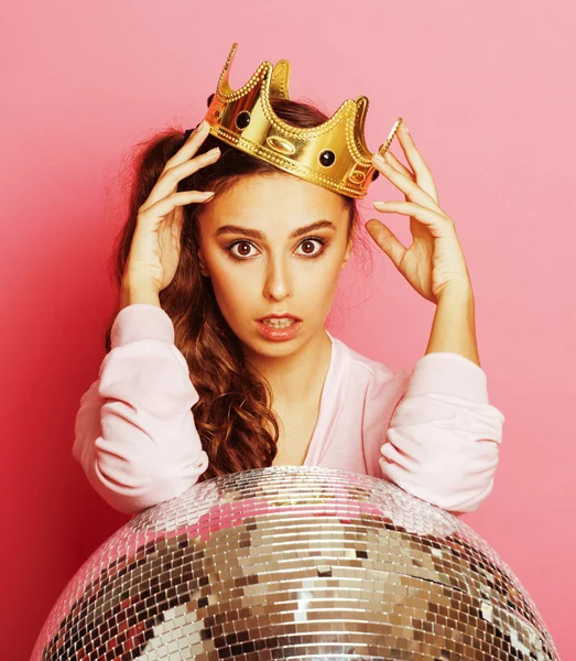 Young cute disco girl on pink background with disco ball and crown