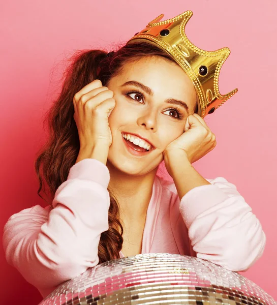 Young cute disco girl on pink background with disco ball and crown