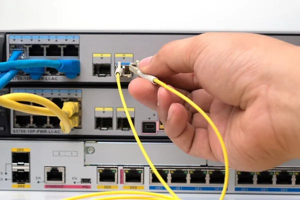 Hand  holding optic fiber cables with connectors pluging in POE