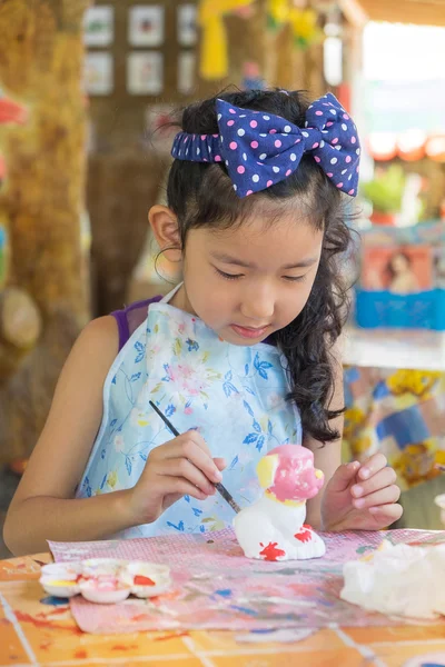 Cute asian girl painting color on the plaster statue.