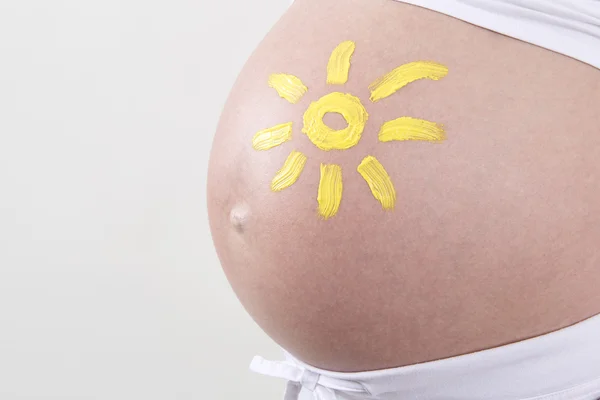 Pregnant woman with yellow sun painted on her belly