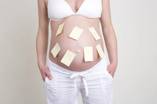 Pregnant woman with lots of yellow labels on her belly