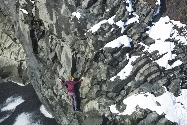 Woman climbing up basalt rocks, Iceland