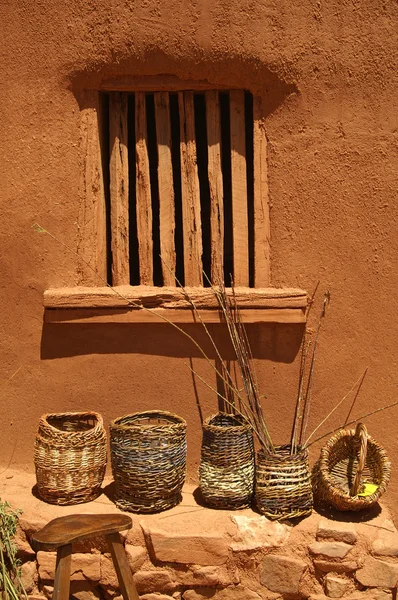 Baskets against an adobe wall.