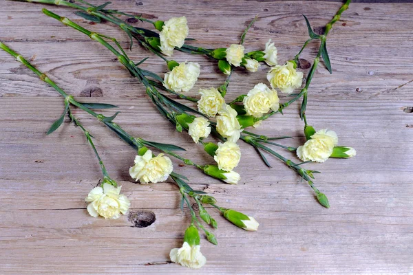 Small yellow carnations on an old wooden table
