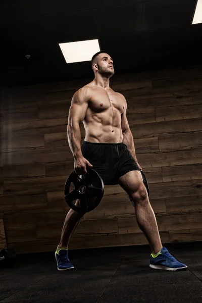 Handsome man with big muscles, posing at the camera in the gym