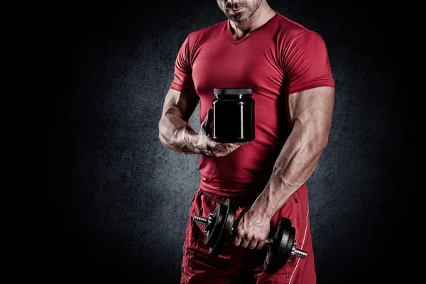 Beautiful young athletic man holding a jar of sports nutrition