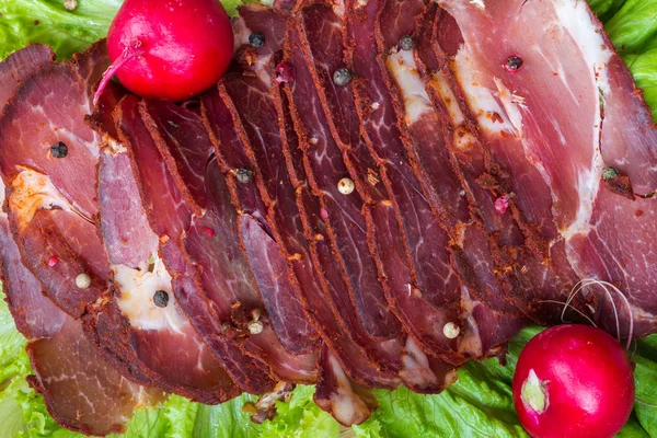 Cut pieces of smoked meat with lettuce, radish and pepper