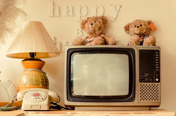 Happy corner of a house with decoration of words saying think happy be happy, bear dolls, old telephone, vase, pot, lamp, plant, bird feather, basket, television