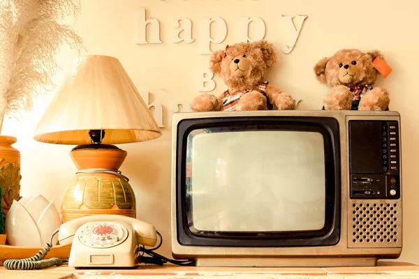 Happy corner of a house with decoration of words saying think happy be happy, bear dolls, old telephone, vase, pot, lamp, plant, bird feather, basket, television