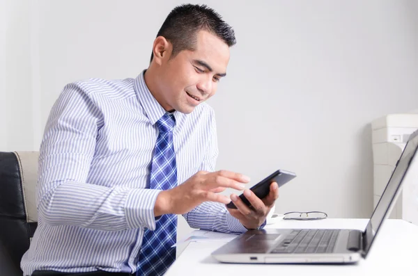 Smiling asian business man using mobile smart phone in office