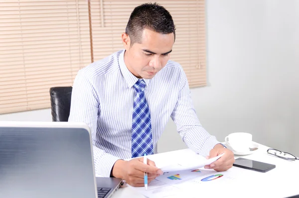 Asian business man looking at document in work place office