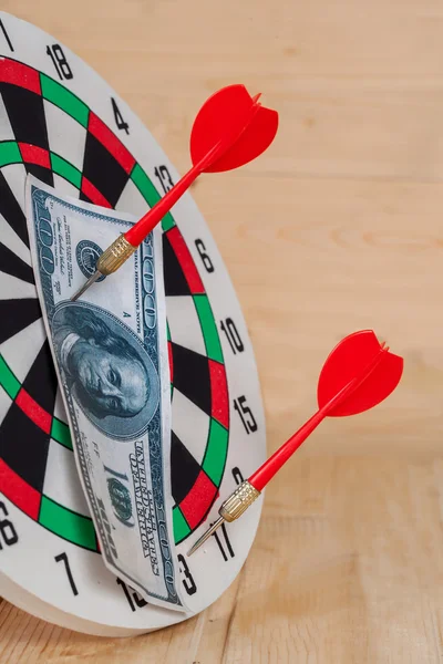 Dart arrow hitting in bullseye on dartboard with money