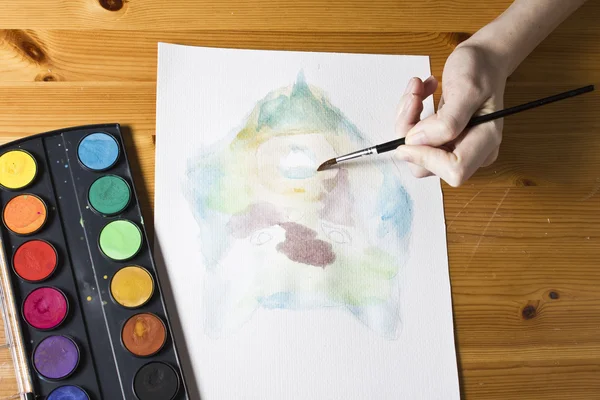The artist paints a picture Wolf using brush and watercolor colorful painting set.