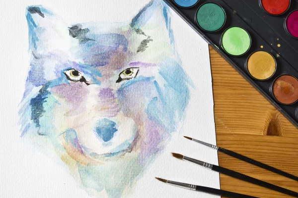 Lor painted picture Wolf. Brushes, painting watercolor colorful set on wooden background.