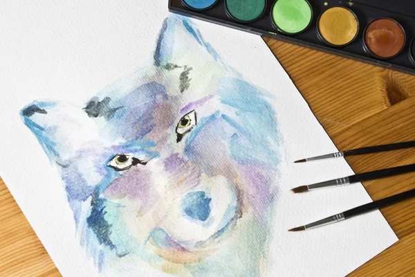 Watercolor painted picture Wolf. Brushes, painting watercolor colorful set on wooden background.
