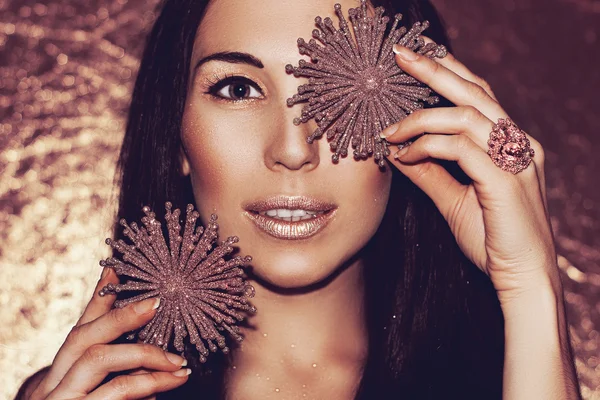 Smiling young beautiful woman brunette with Christmas decorations bronze snowflakes. Fashion make-up. Model shot.